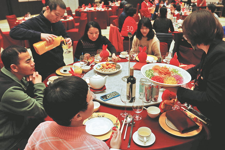 At a restaurant's Lunar New Year's Eve dinner, a waitress serves food to customers.