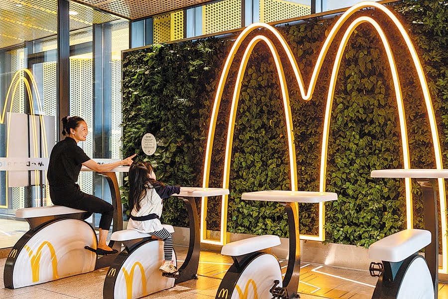 Consumers try wireless mobile phone charging by riding spin bikes to generate electricity at the McDonald's zero carbon restaurant in the Shougang Park in Beijing on Sept 10 2022.