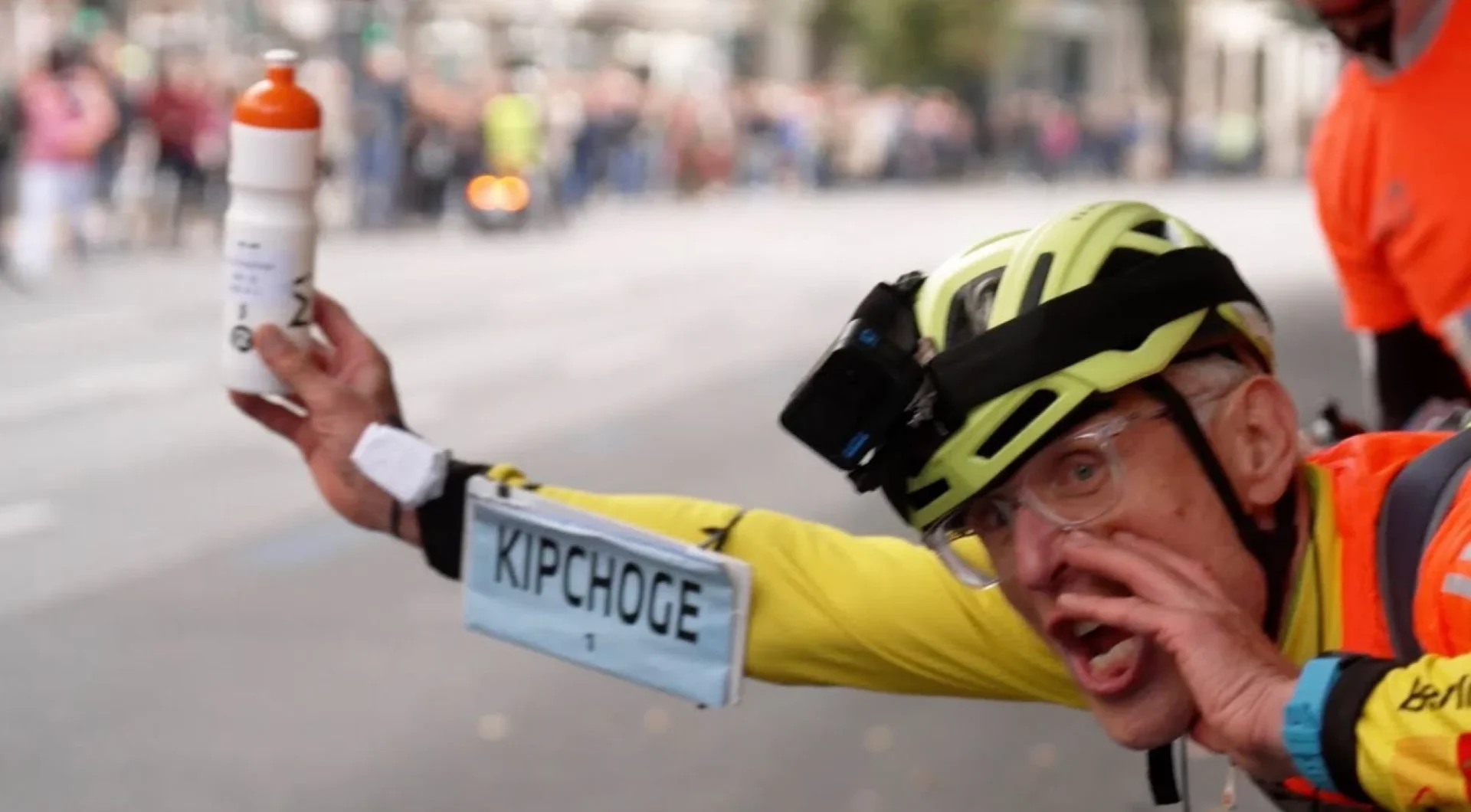 Schulke gets ready to hand off a nutrition bottle to Eliud Kipchoge during the 2023 Berlin Marathon. Photo: Youtube/@FloTrack.