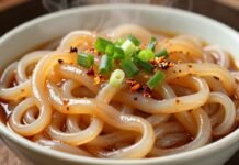 Steaming bowl of pearl noodles with green onions and chili.