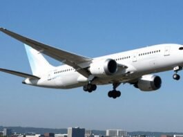 Boeing 787 airplane flying high above a city.