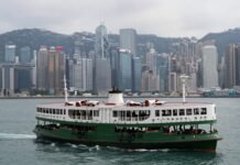Hong Kong harbor with ferry and skyline.